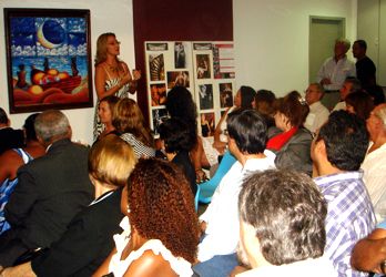 Sandra Serrado palestra com a exposio de fotos e quadros ao fundo